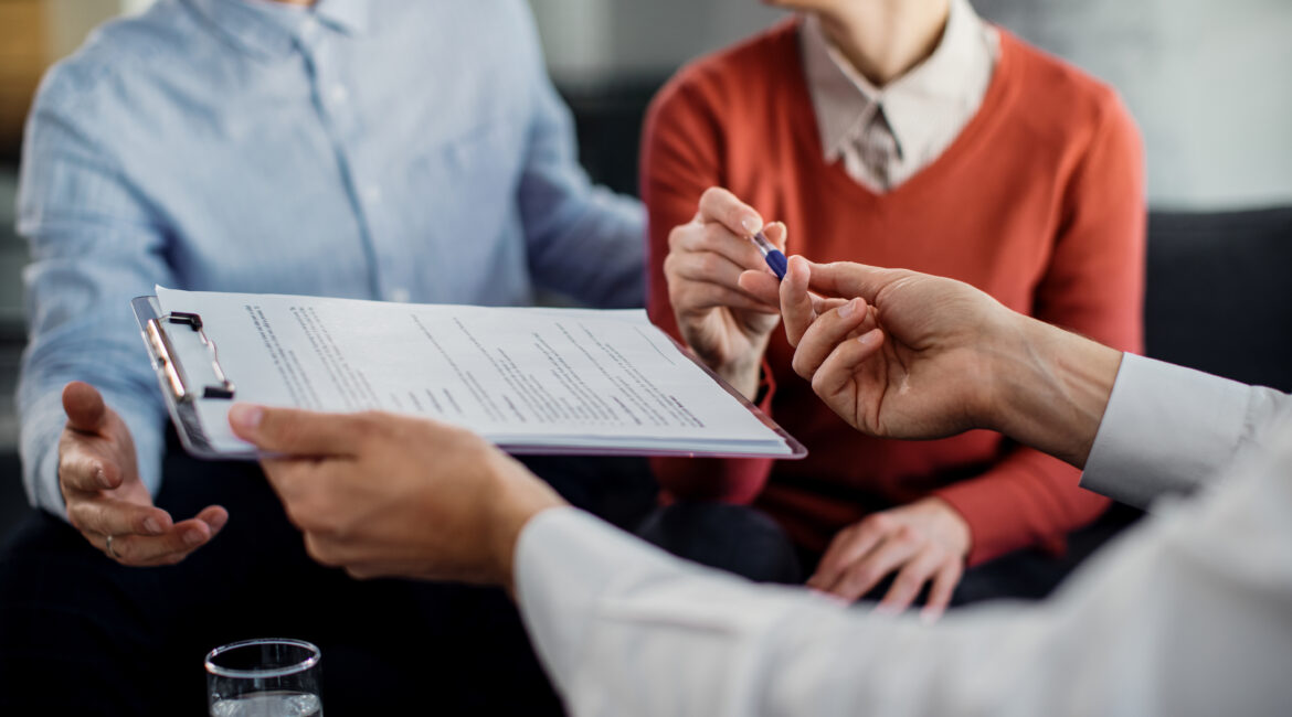 closeup unrecognizable couple signing contract with financial advisor