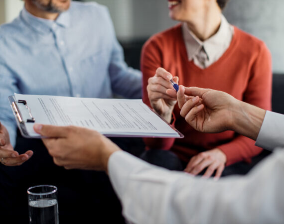 closeup unrecognizable couple signing contract with financial advisor